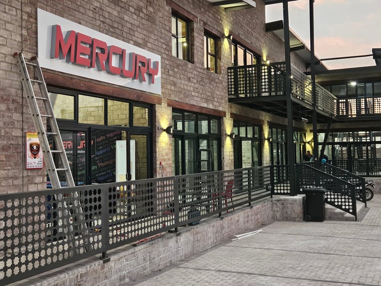 Red Mercury storefront on brick building with black railings, ladder propped against facade, and metal mesh decorative panels